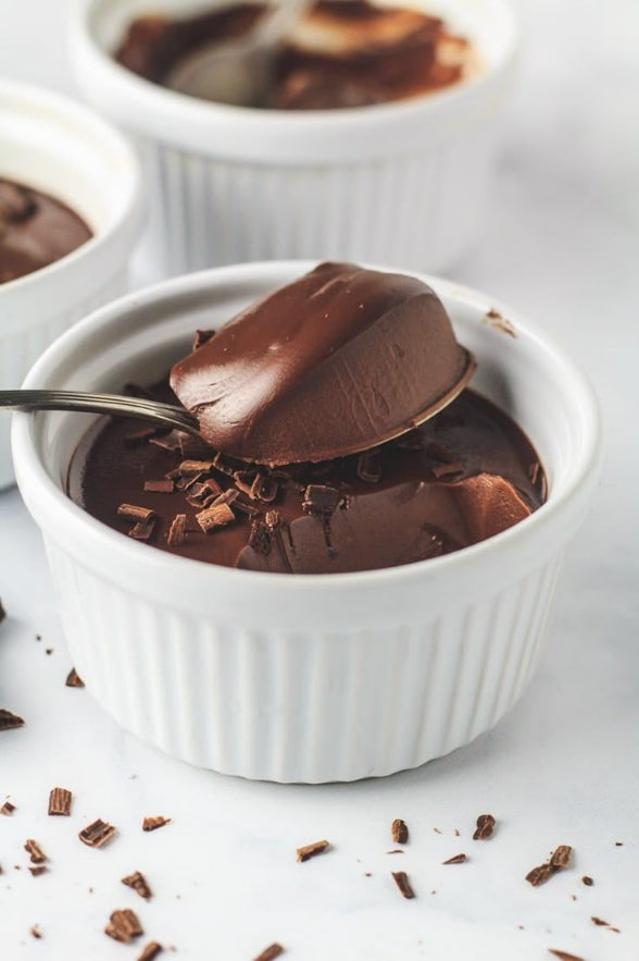 Delicious homemade chocolate pudding served in glass bowls with chocolate toppings, ready to enjoy as a dessert.